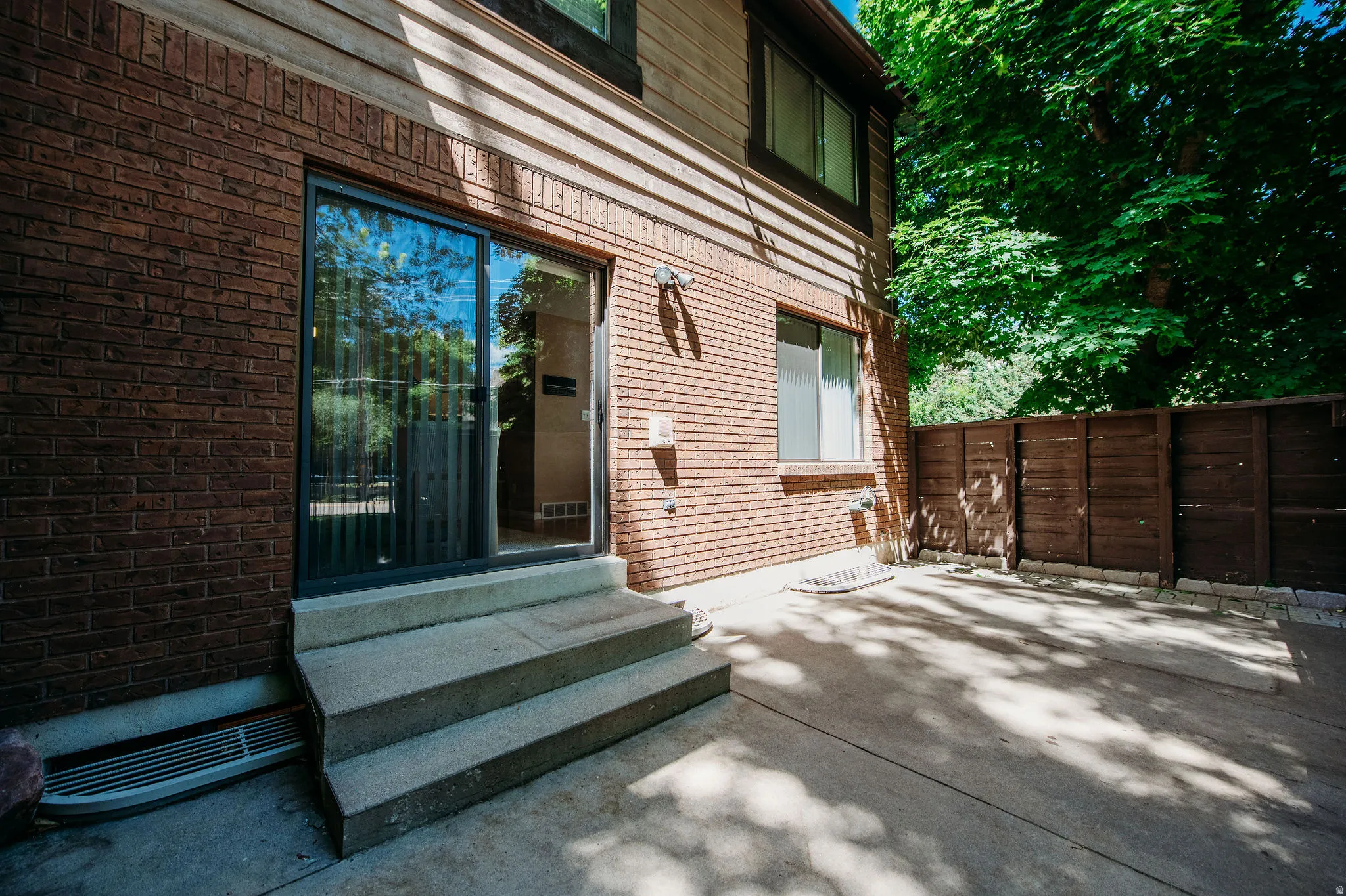 Patio area featuring concrete surfacing, a privacy fence, and mature trees