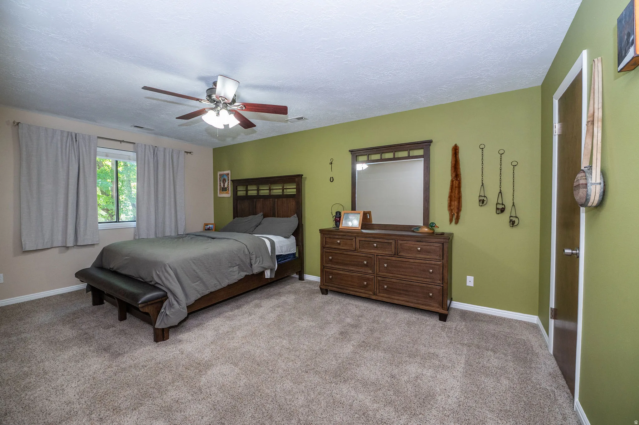 Spacious room featuring neutral carpet flooring, a window offering natural light, and a ceiling fan with integrated lighting