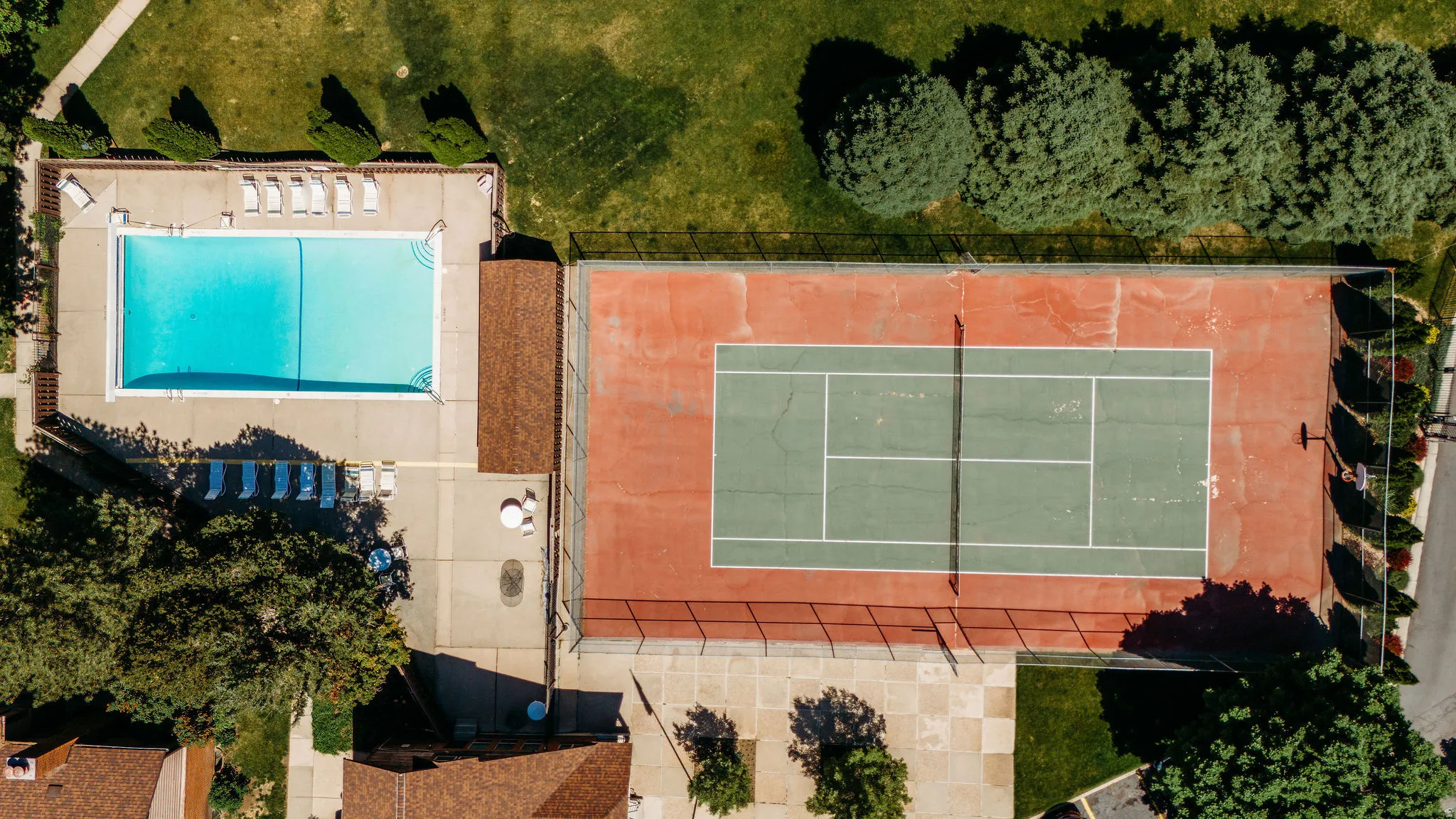 Outdoor tennis court with a green playing surface and pool