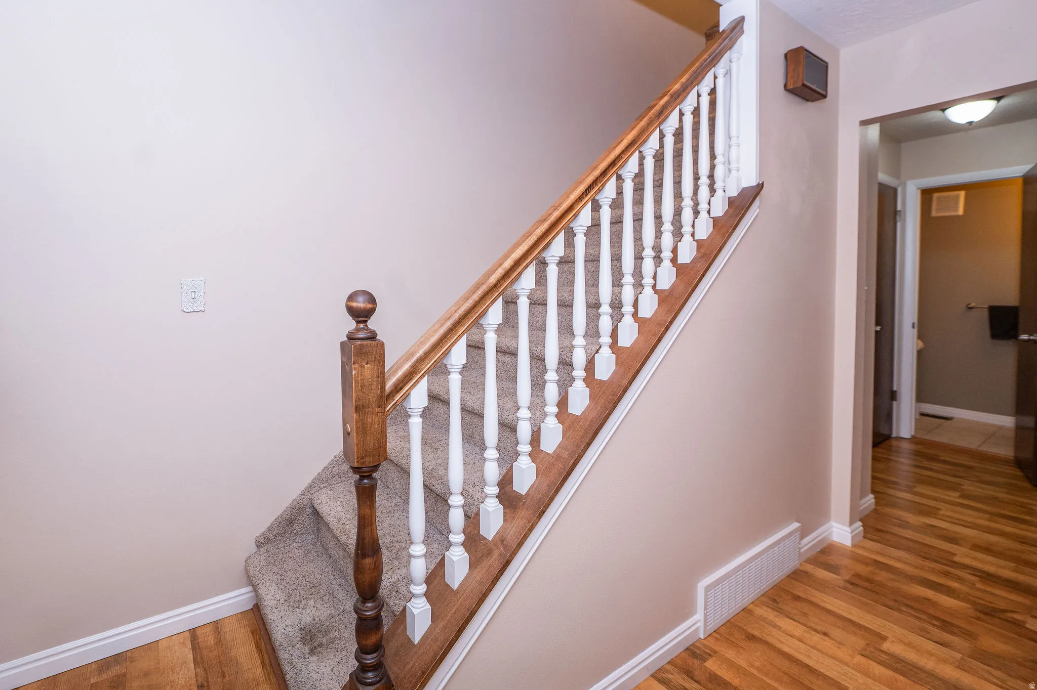 Carpeted staircase with white balusters and a wood-finish handrail