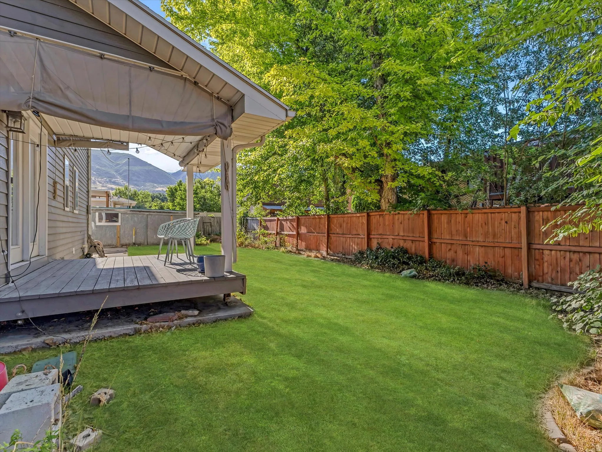 Expansive green lawn featuring a wooden fence and mature trees
