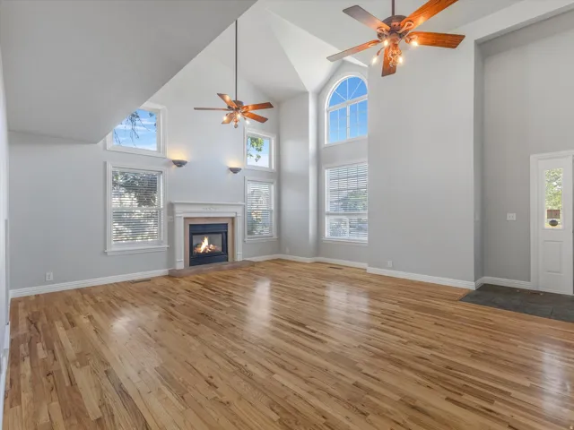 Spacious living area featuring vaulted ceilings, wood-finish flooring, and a fireplace with a decorative mantel