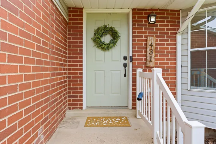 Brick exterior featuring a light-colored entry door with dark hardware