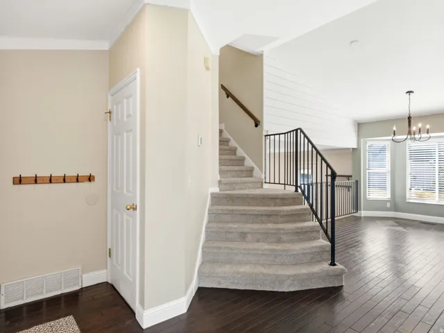 Carpeted staircase with black wrought iron balusters and a wood handrail