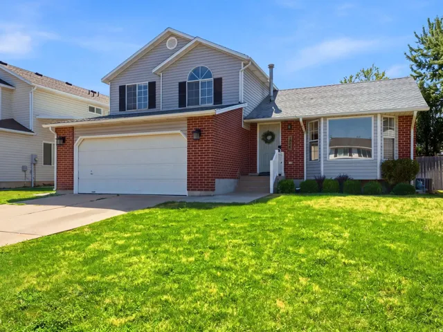 Two-story residence featuring a brick and siding exterior, an integrated two-car garage, and a bay window