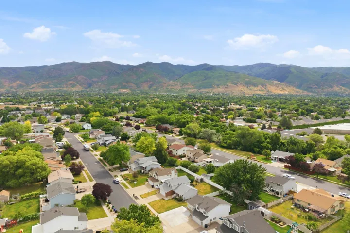 Expansive aerial panorama showcasing a suburban neighborhood with mature trees and mountain scenery