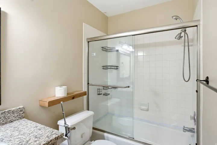 Upper level full bathtub with white subway tile surround, and handheld shower fixture