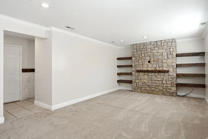 Spacious family room featuring stone accent wall with wood shelving