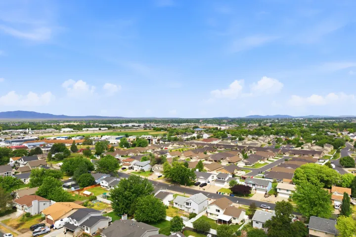 Expansive aerial perspective showcasing a residential neighborhood with numerous single-story homes, mature trees, and paved streets