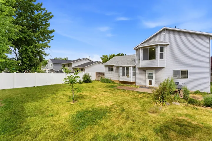 Spacious backyard featuring a manicured lawn and a white privacy fence