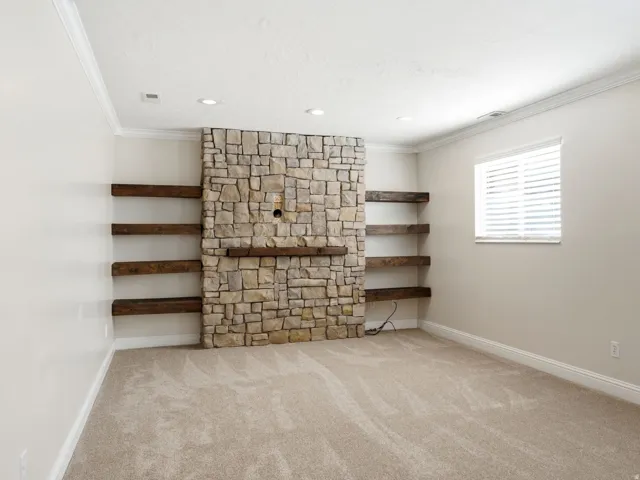 Spacious family room featuring stone accent wall with built-in shelves