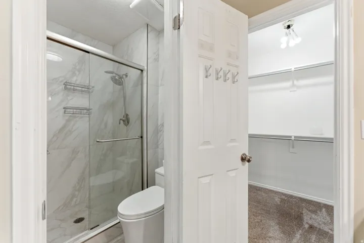 Primary bedroom bathroom-updated shower and tile-view of walk-in closet