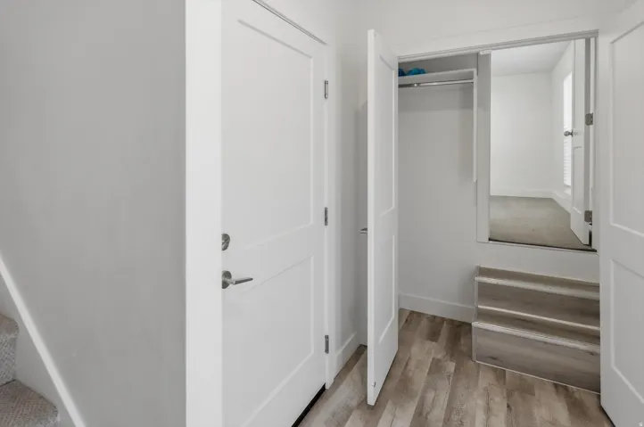 Entry area featuring wood-finish flooring, white paneled doors, and a built-in closet with a hanging rod