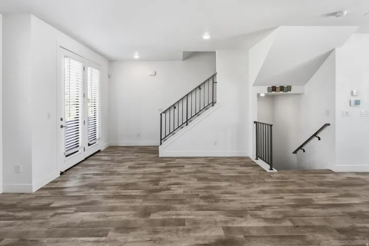 Open-concept living area with wood-finish flooring, white walls, and recessed lighting