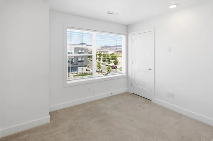 Bright interior space featuring a large window, neutral carpeting, white trim, and a recessed ceiling light