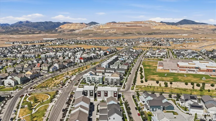 Expansive aerial panorama showcasing a developed residential community with diverse housing styles, structured streets, and green spaces