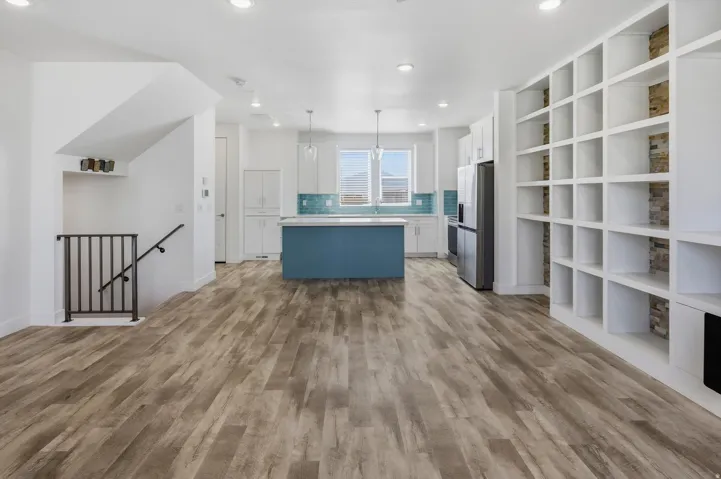 Open concept living area featuring wood-finish flooring, recessed lighting, and built-in shelving with stone accent panels