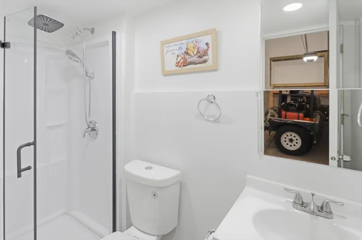 Bathroom featuring a white shower stall with a clear glass enclosure and black trim, a square rain shower head, and an additional handheld shower fixture