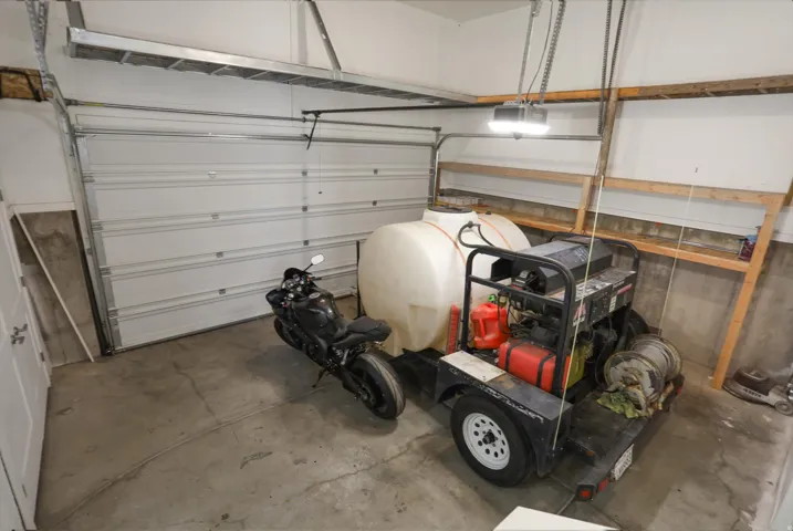 Garage featuring a concrete floor, overhead door, and built-in shelving