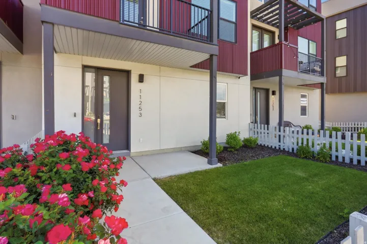 Modern exterior featuring a covered entry and a white picket fence enclosing a compact lawn area
