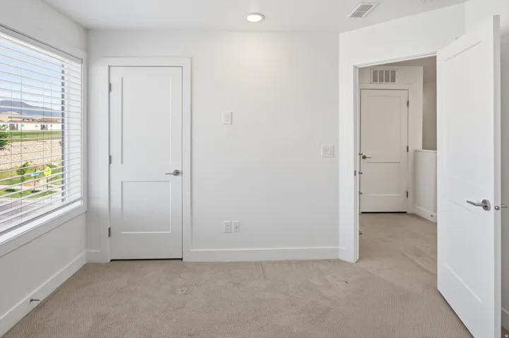 Neutral tone carpet flooring and crisp white walls provide a versatile backdrop