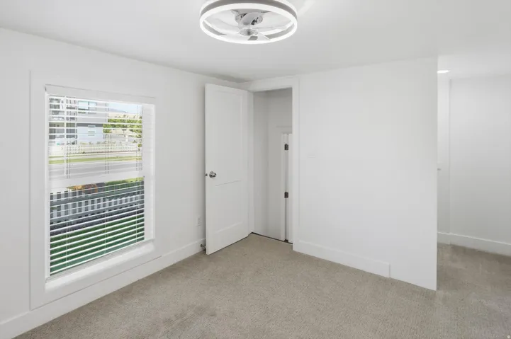 Room featuring a contemporary ceiling fan with integrated lighting, a single window with blinds, and neutral carpeting