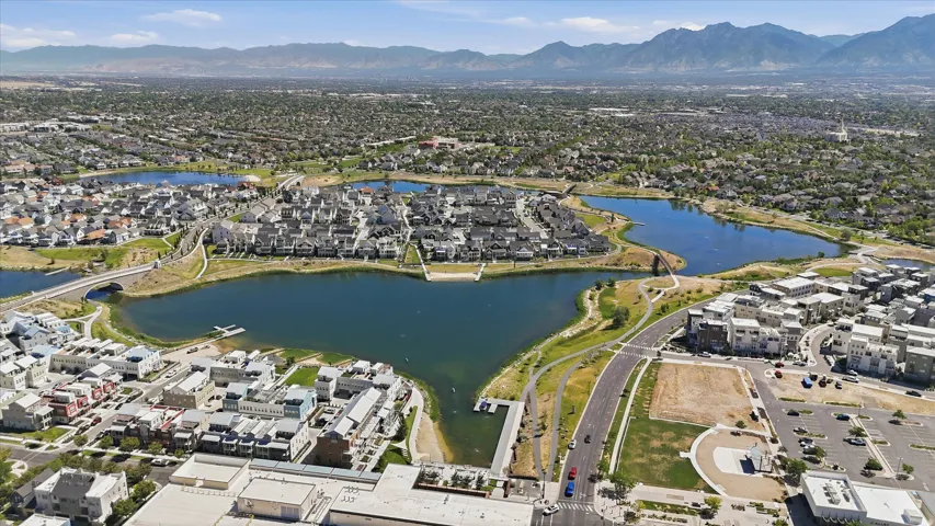 Expansive aerial view showcasing a large residential community featuring multiple lakes, surrounding green spaces, and mountain scenery