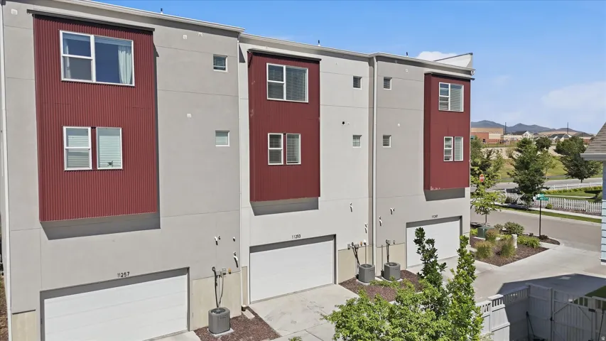 Modern townhome exterior featuring light gray stucco and prominent red corrugated metal accent panels