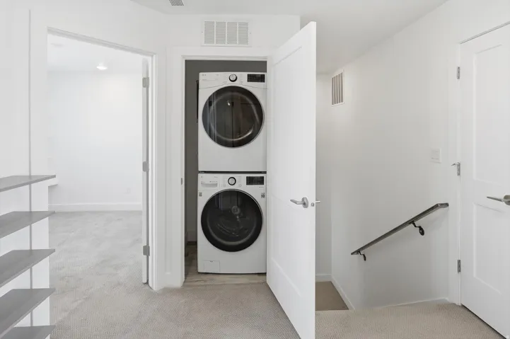 Integrated laundry area featuring stacked front-loading washer and dryer units