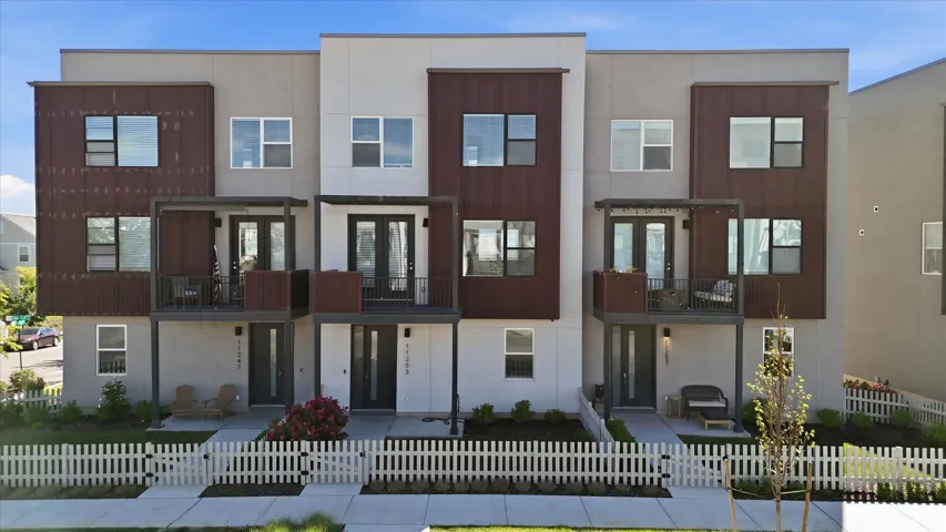 Modern townhouse facade featuring a combination of light-colored stucco and dark-toned paneling