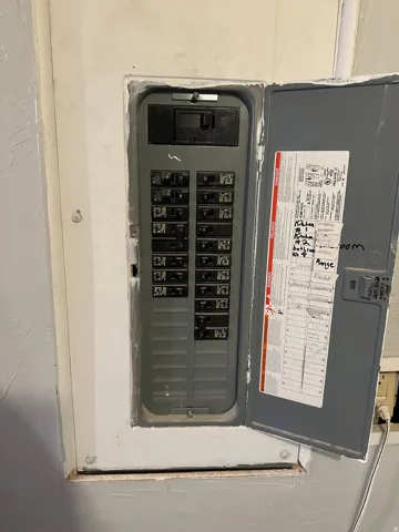 Electrical panel with multiple circuit breakers and an open cover