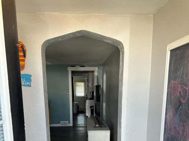Arched entryway leading to interior spaces with wood-finish flooring