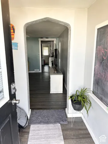 Entryway featuring a pointed arch structural opening and wood-finish flooring
