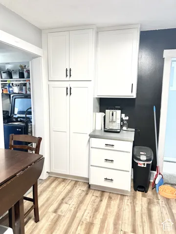 White shaker-style cabinetry featuring matte black hardware, integrated floor-to-ceiling pantry storage, and stone-finish countertop
