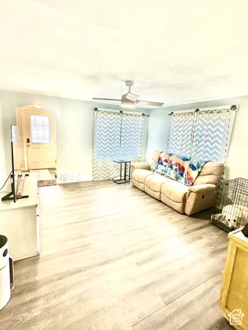 Interior space featuring wood-finish flooring, a ceiling fan with integrated lighting, and an arched doorway