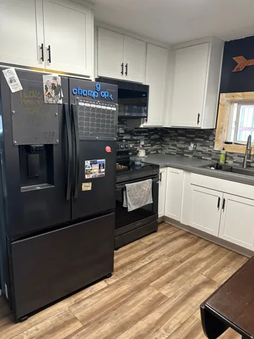 Kitchen featuring wood-finish flooring, white cabinetry, dark countertops, and a mosaic tile backsplash