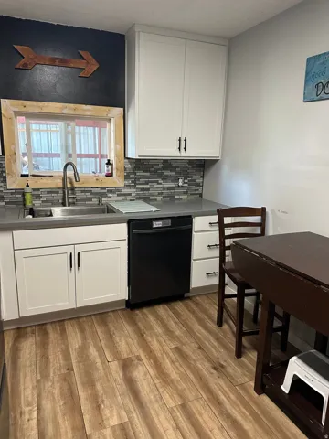 Updated kitchen featuring white shaker cabinetry, a mosaic tile backsplash, and wood-finish flooring