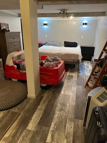 Spacious room featuring wood-finish flooring, a ceiling fan, and wall-mounted sconce lighting