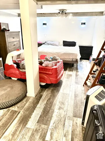 Wood-finish flooring throughout, two wall-mounted light fixtures, and a multi-bulb flush mount ceiling light