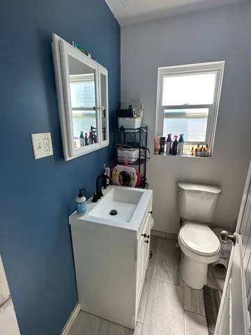 Bathroom featuring a white vanity with an integrated sink, matte black faucet, and white framed medicine cabinet