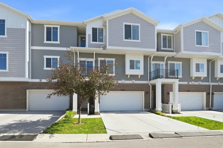 Contemporary multi-level townhome featuring a mix of siding and stucco finishes, brick accents, and individual garage access