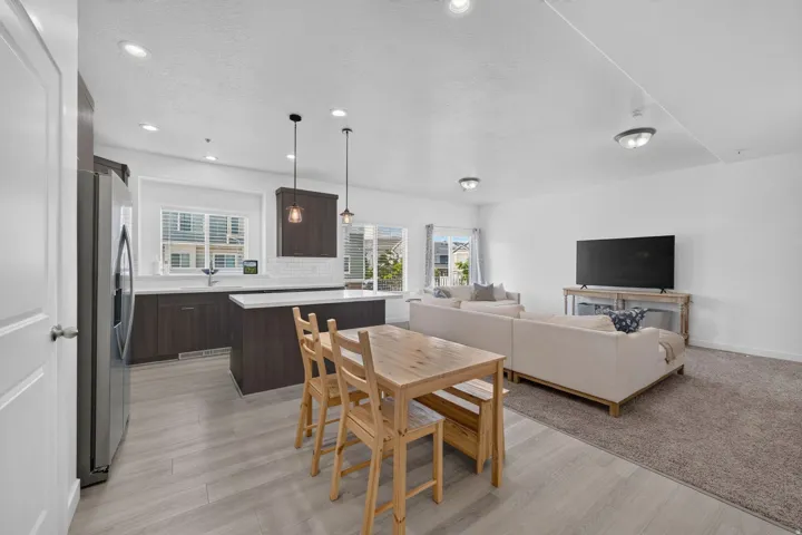 Open-concept living space featuring a kitchen with dark wood-finish cabinetry, white countertops, and a subway tile backsplash