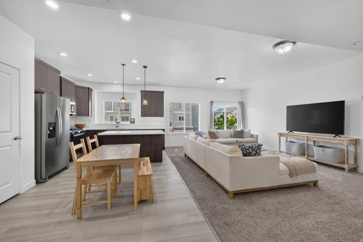 Open concept living area featuring wood-finish flooring, recessed lighting, and a modern kitchen with dark cabinetry and stainless steel appliances