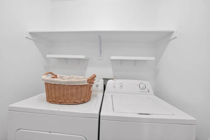 Dedicated utility area featuring a built-in shelf system and two wall-mounted shelves for storage