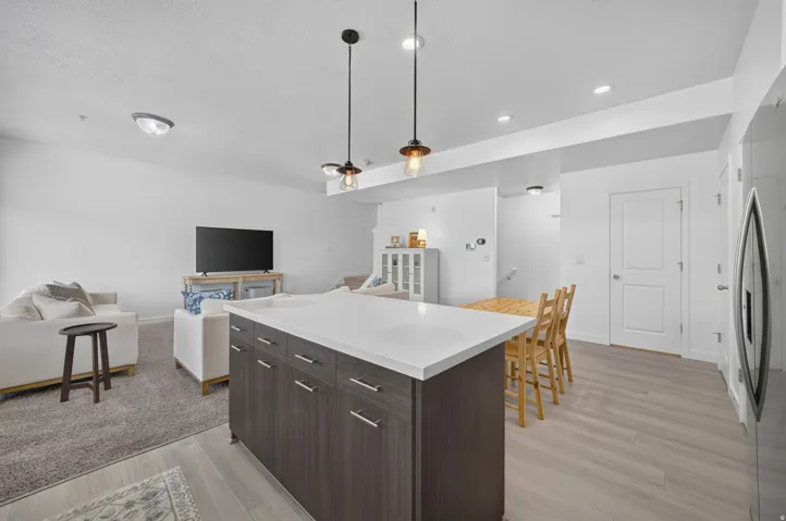 Open-concept living area featuring a kitchen island with storage cabinetry, light wood-finish flooring, and recessed ceiling lighting