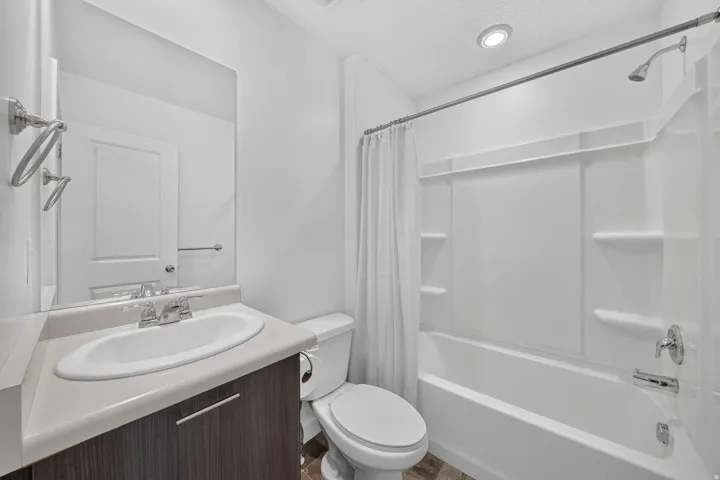 Contemporary bathroom featuring a dark wood-finish vanity with a light countertop, an oval undermount sink, and a chrome faucet