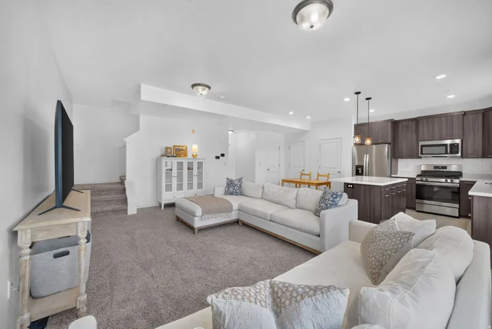 Open-concept living area featuring a kitchen with dark wood-finish cabinetry, stainless steel appliances, and a white subway tile backsplash
