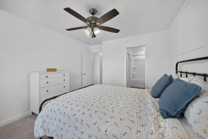 Bedroom featuring a ceiling fan with integrated lighting, board and batten wall detailing, and soft carpet flooring