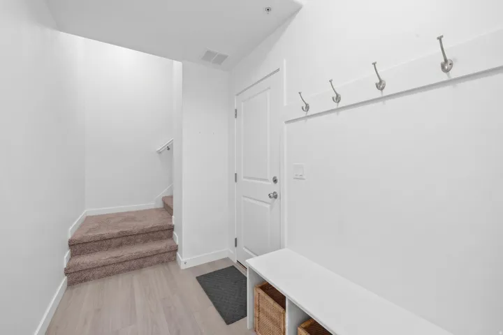 Entryway featuring light wood-finish flooring, a built-in storage bench with two cubbies, and a wall-mounted coat rack with four hooks