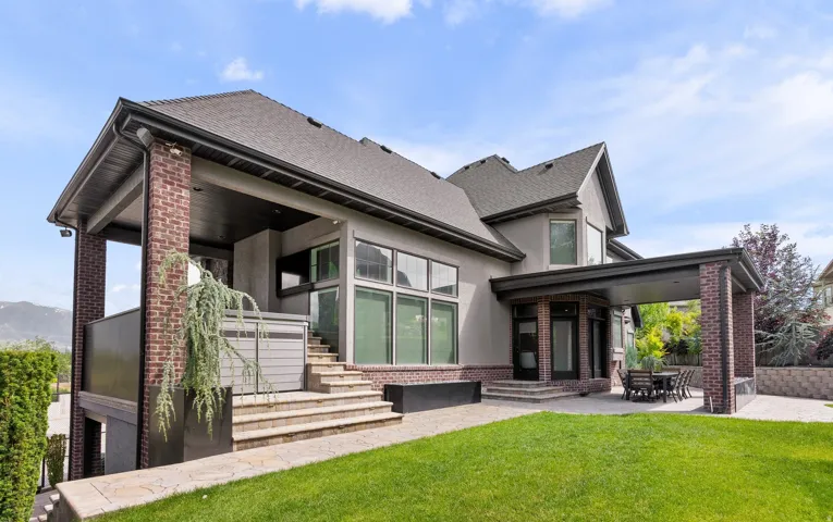Contemporary two-story residence featuring a brick and stucco exterior, a covered patio, and a tiered stone stairway